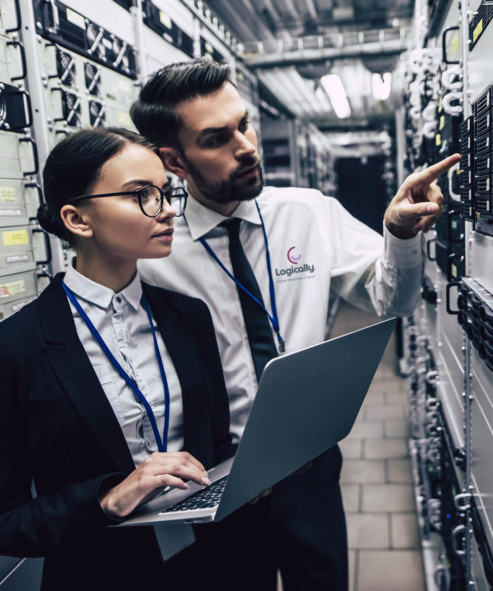 two logically network engineers observing a server in the server room with the female employee holding a laptop