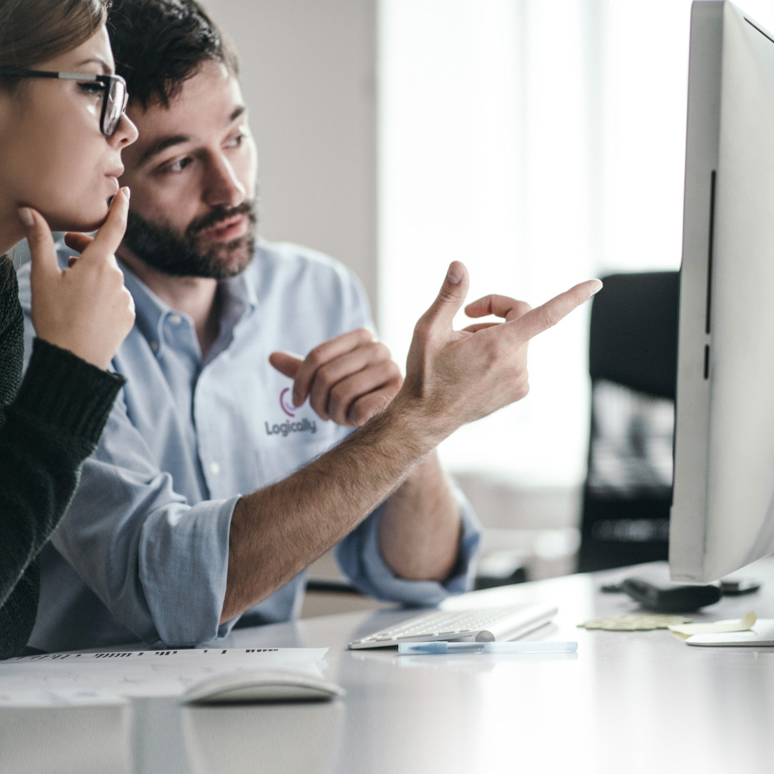 Man explaining to a woman something they both see on a desktop