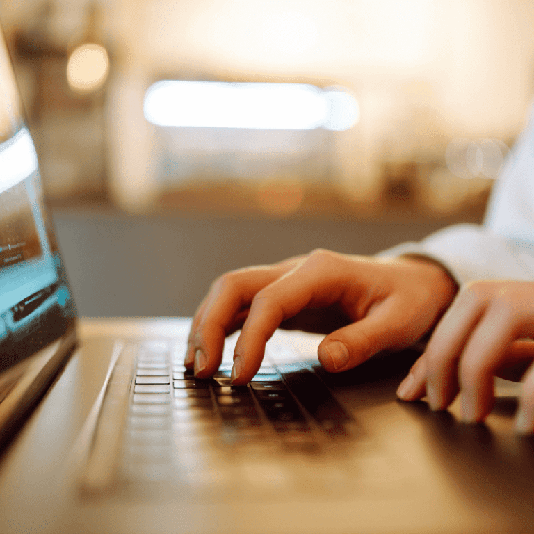 Hands typing on a laptop