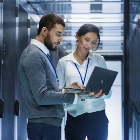Man and woman standing side by side reviewing an IT report on a laptop