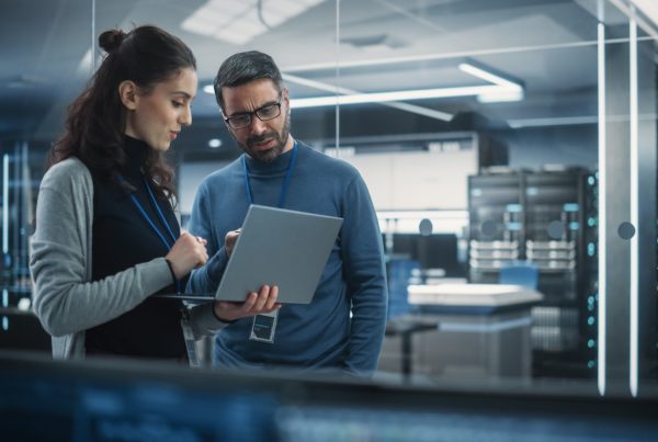 two tech professionals looking at incident response plan on laptop